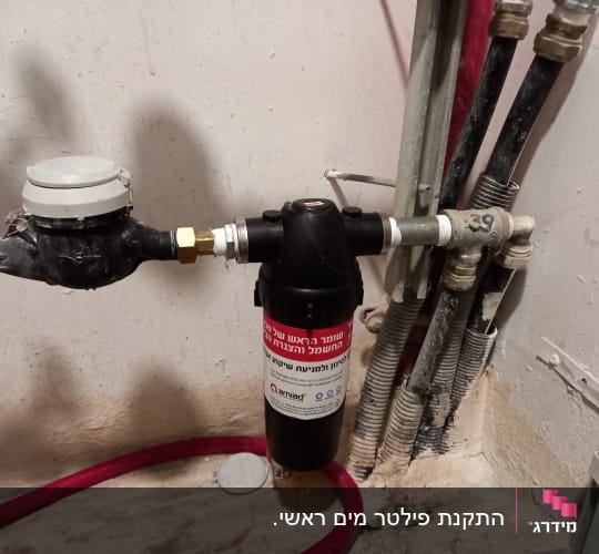 מד מים ומסנן מחוברים לצינורות על קיר